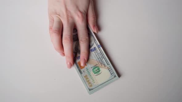 An unidentified hand holds out a wad of money on the table. alt