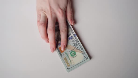 An unidentified hand holds out a wad of money on the table.