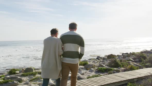 Caucasian couple enjoying free time by sea on sunny day walking path alt