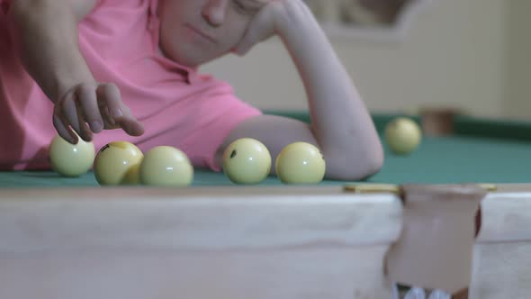 Young Man Playing with Billiard Balls While Lying on Billiard Table alt