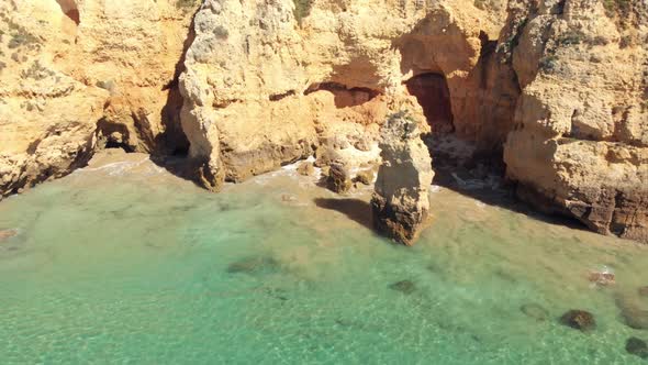 Cliffs and caves of pristine Atlantic Ocean coast,  Lagos, Algarve, Portugal. Aerial pullback alt
