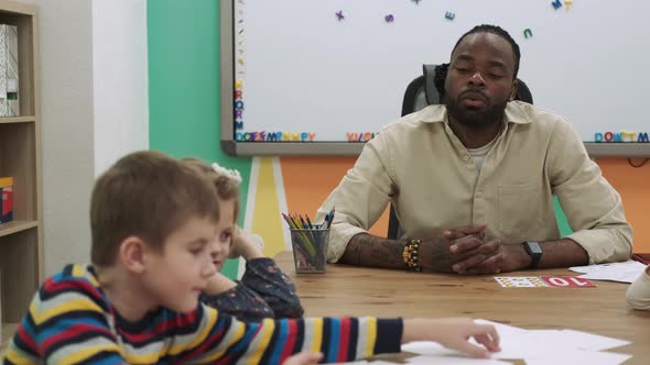 An African American Teacher Teaches a Group of Children Numbers Using Flashcards alt