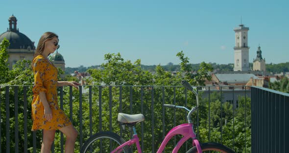 Young Stylish Caucasian Female Near a Bicycle. Portrait of Attractive Young Woman in Sunglasses alt
