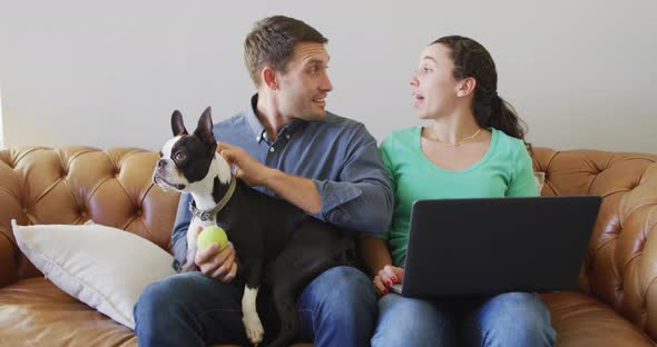 A young caucasian couple talking and paying their bills using a laptop alt