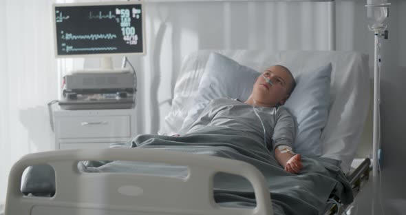 Unhappy Sick Kid with Cancer Lying in Hospital Bed alt