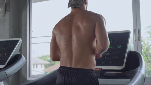 Muscular man running on treadmill at the fitness