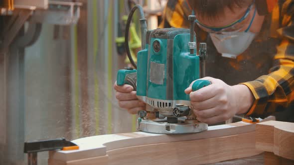 Man Woodworker Polishes a Wooden Plank with a Special Equipment alt
