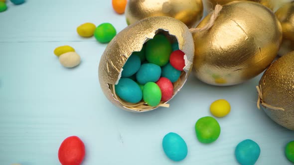 Golden Decorative Easter Eggs Filled with Colorful Candies on Wooden Table Close Up