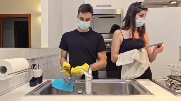 Happy family dish washing together at home while wearing face masks. alt