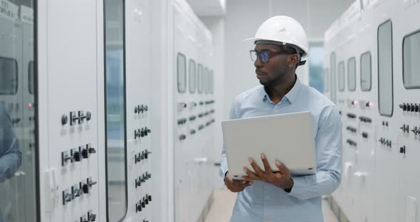 Man Using a Laptop While Working in a Server Room alt
