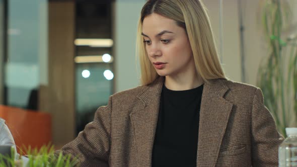 Two Young Female Creatives Sitting in an Office Working Together in Discussion at a Laptop Computer alt