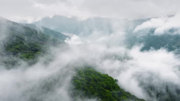 Aerial View of Misty Forest Clouds Above Mountain alt