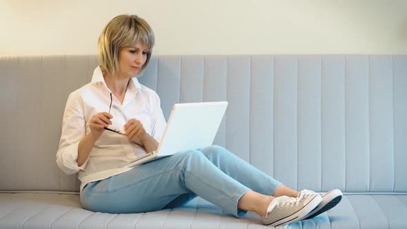 A Beautiful Elderly Woman is Happy to Communicate Online with a Friend or Relative on a Laptop