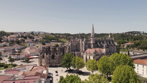 Aerial pan shot capturing gothic architecture Batalha Monastery and townscape, central Portugal. alt
