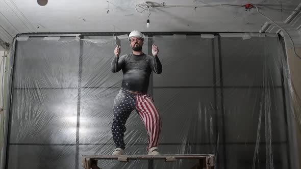 Fat Bearded Adult Man in Protective Helmet and USA Flag Print on Pants Remove Construction Whitewash alt