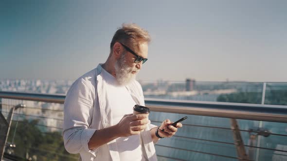 Active Pensioner in Glasses Walks Checking News on Phone alt