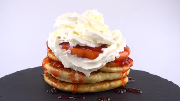 Pancakes with strawberry topping and whipped cream on a white background.  alt