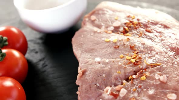 Sirloin chop, cherry tomatoes and coriander seeds on chopping board alt