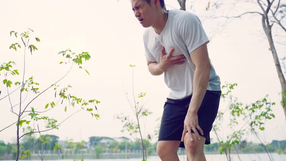Asian attractive sport male feel heart attack while running on street. alt