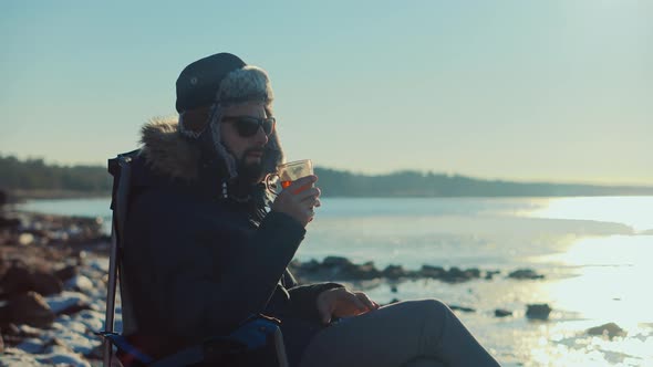 Man Warming Hands Steaming Cup Of Mate Tea. Male Hands With Mug Of Hot Drink Cold Winter Outdoors. alt