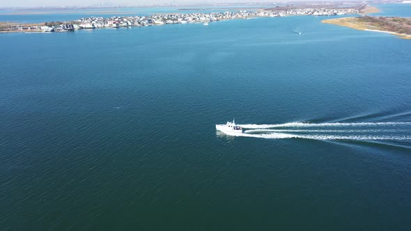 An aerial shot over Jamaica Bay in Queens, NY. The camera trucks left then pan left to follow a boat alt