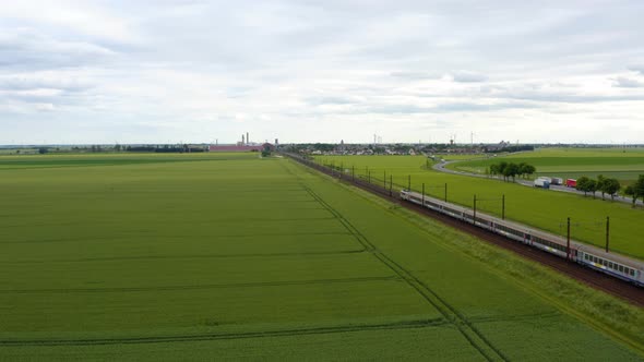 Aerial view of local train traveling through green fields  alt