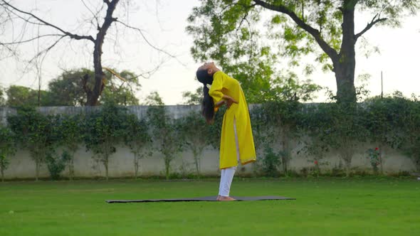 Standing Backbend Yoga Pose or Anuvittasana is being done by an Indian woman alt