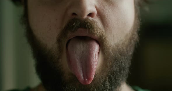 A Cropped Portrait of a Bearded Man Taking a Medicine Pill