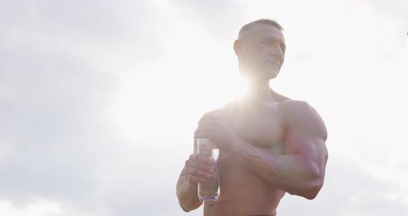 Strong Shirtless Man Drinking Water After Intense Workout alt
