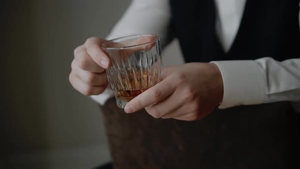 Businessman in suit is holding whiskey glass