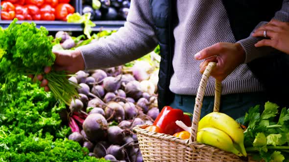 Couple selecting vegetables from organic section alt
