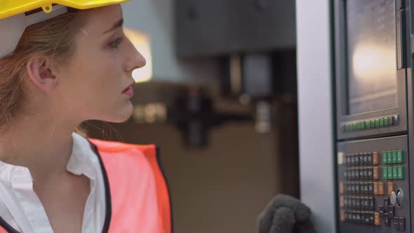 Caucasian female industrial worker checking and repairing machine