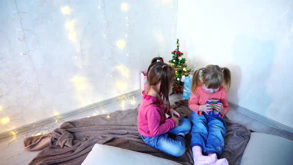 Active Young Children of Girls Laugh and Fool Around Sitting on Floor on Rug