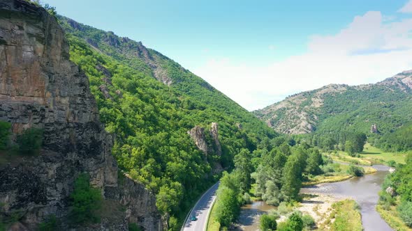 Panorama Aerial View Of A Scenic Road In Between The Mountains And River During A Vibrant Sunny Day