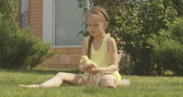 Wide Shot Portrait of Cheerful Caucasian Girl Playing with Duckling Outdoors and Leaving. Cute Child alt