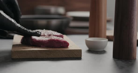 Slow Motion Orbit Shot of Man Rub Seasoning Into Raw Beef Steak on Oak Board alt