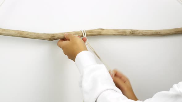 A woman makes home decor in Boho style. Woman making handmade decor weaves macrame alt