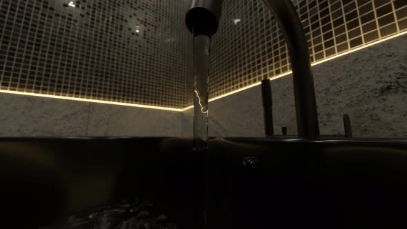 Black Tap Flowing Water And Illuminated From Yellow Led Lights