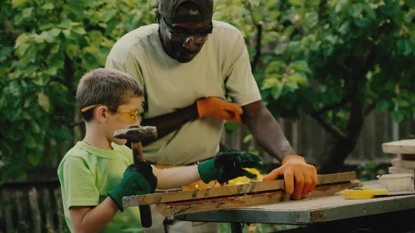 African American Carpenter Teaches White Boy to Hammer Nail