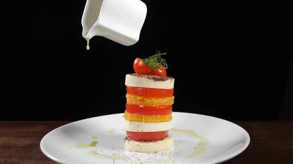 Pouring Olive Oil on Mozzarella Salad in Slow Motion. Food Footage on Black Background. Italian alt