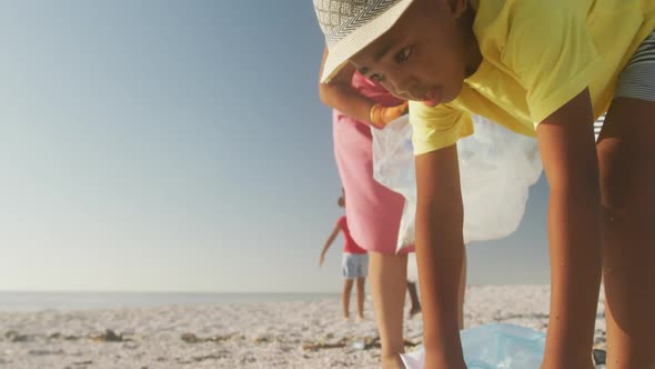 Senior african american couple with grandchildren segregating waste on sunny beach alt