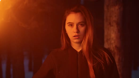 Young Woman with Braces Waving with Torch Standing in Winter Forest alt