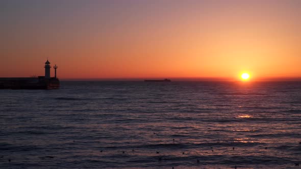 Sunrise Over the Sea  We See a Cargo Ship On the Horizon  Pier With a Beacon