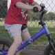 Close-up slow motion shot of a young boy riding a balance bike along a sidewalk in a residential nei - VideoHive Item for Sale