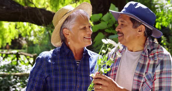 Senior couple smelling flowers alt