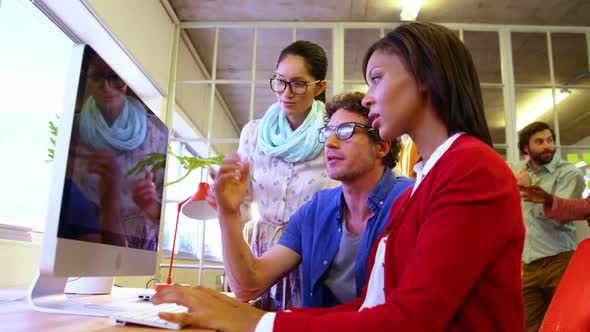 Group of business executives interacting over computer alt
