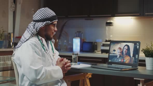 Arabic Doctor with Kandora Making Video Consultation on Computer with Mom and Child