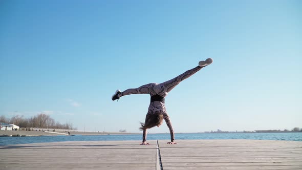 Young Athletic Female Gymnast Performs Handstand Pontoon Near Blue Lake alt