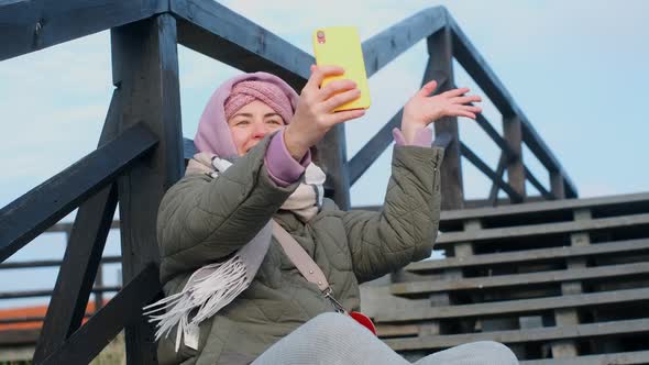Blogger Woman in Warm Clothes Records Selfie Video By Her Phone alt