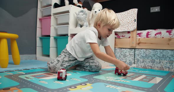 Cute Little Boy Playing with Toy Firetruck in Child Bedroom in Home alt